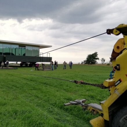 Foto: Evakuators aizvelk 'Māju-kuģi' pa pļavu; Lūsiņš 'piemirsis' informēt VVD